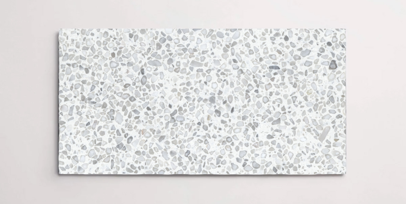 A single white terrazzo marble tile with small grey chips throughout