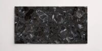A single dark grey terrazzo marble tile with various sized aggregates throughout