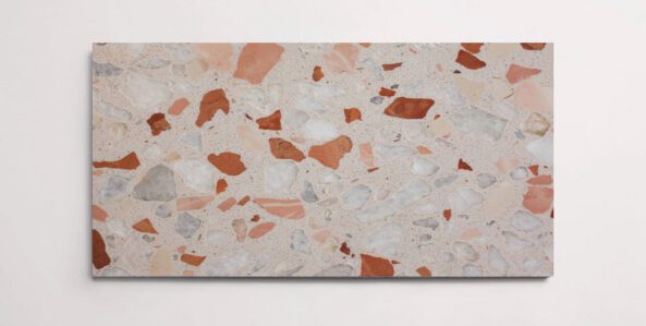 A single terrazzo marble tile with various sized aggregates throughout in shades of blush and red