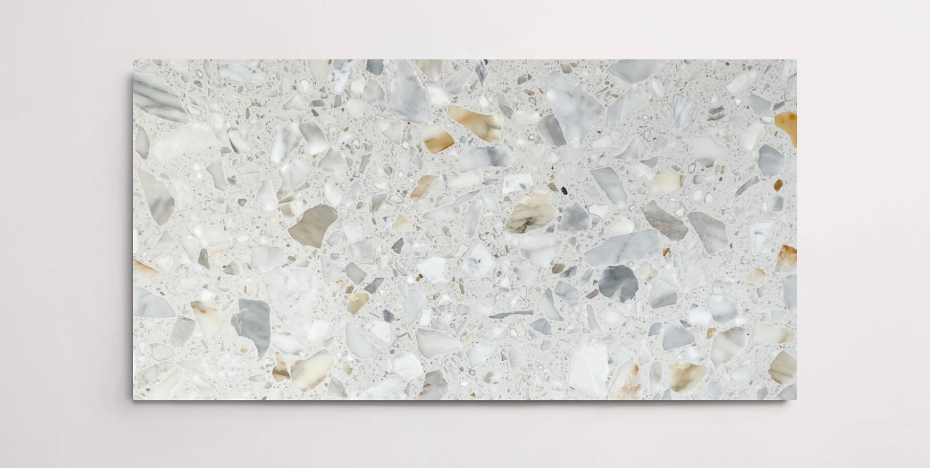 A single white terrazzo marble tile with various sized aggregates throughout in shades of grey white and brown