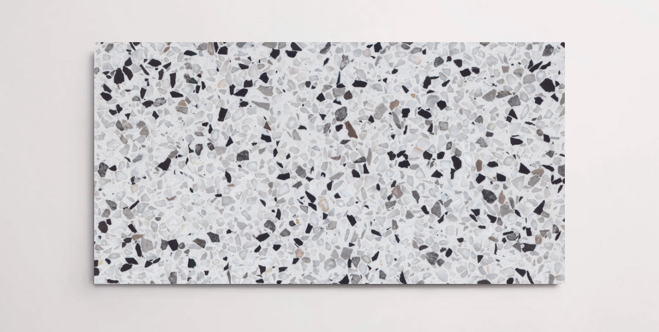A single grey terrazzo marble tile with various sized chips throughout in shades of white and black