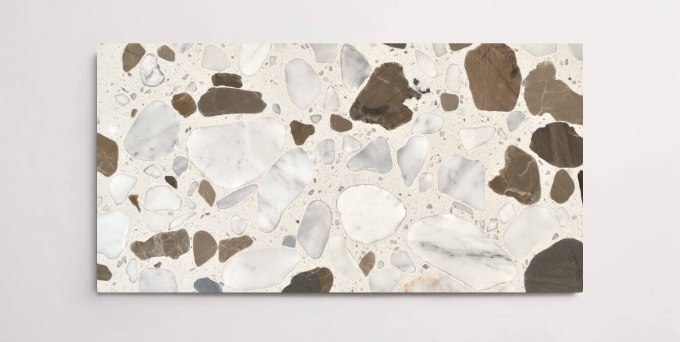 A single cream terrazzo marble tile with various sized chips throughout in shades of white, grey, and brown
