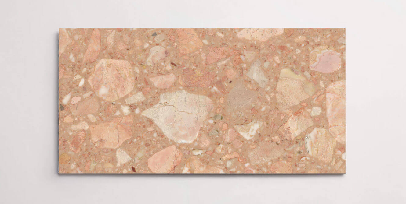 A single blush colored terrazzo marble tile with various sized chips throughout