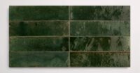 Eight stacked 2.25" x 9.5" dark green wall tiles in a glossy finish