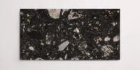 A single black terrazzo marble tile with various sized aggregates throughout