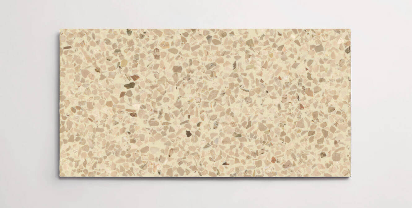 A single beige colored terrazzo marble tile with various sized chips throughout