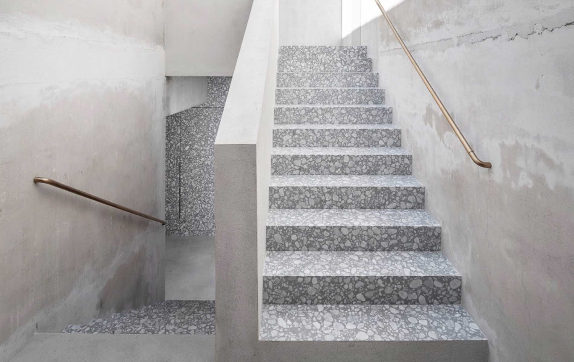 A grand interior staircase made of grey and white terrazzo marble.